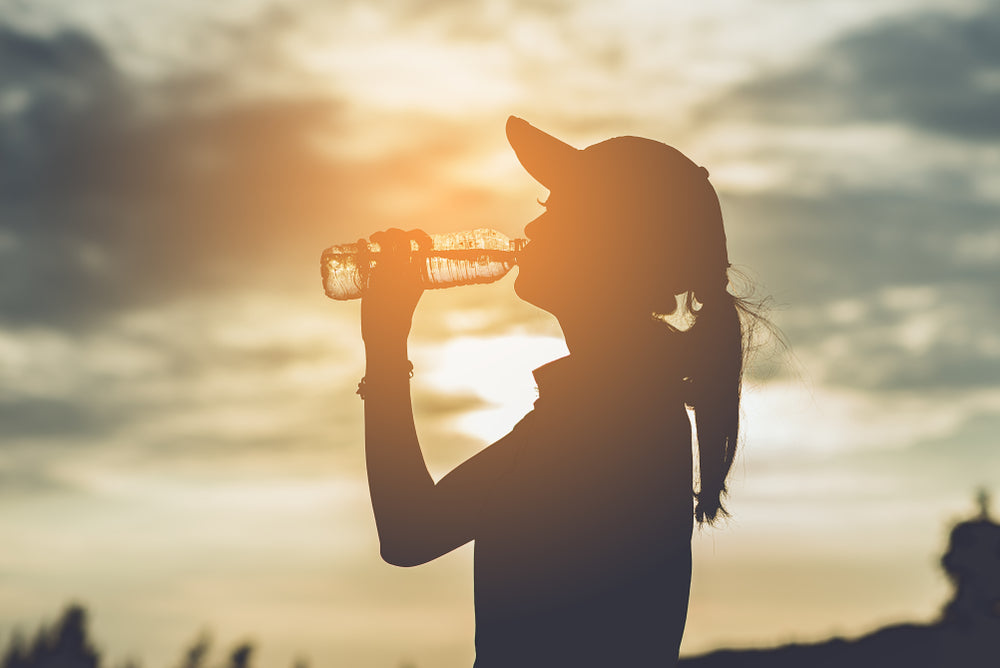 Young woman drinking water in the sun during extreme heat