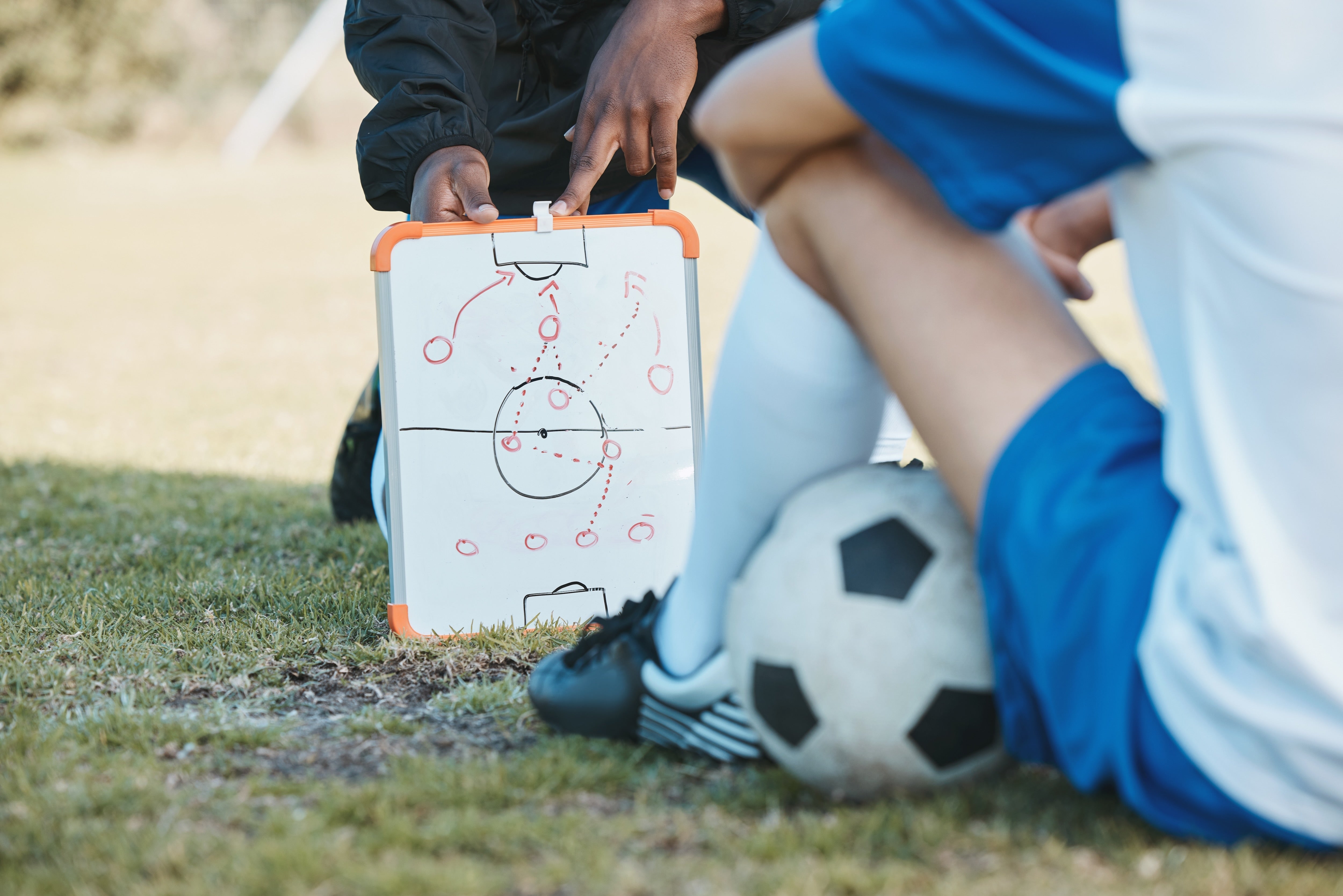 Soccer coach on the sideline with clipboard managing athletes in summer heat