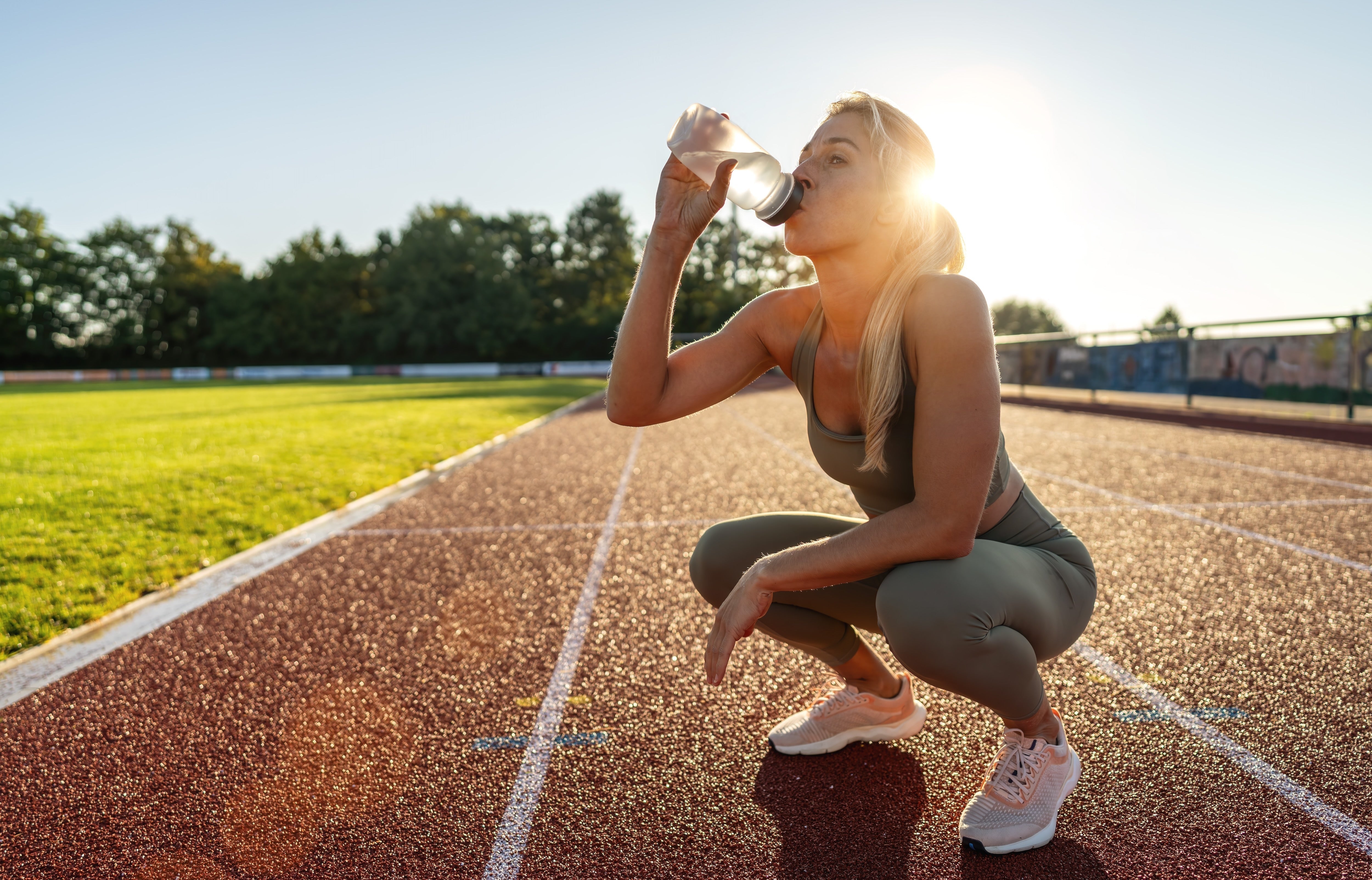 Female athlete hydrating and recovering after track training in heat
