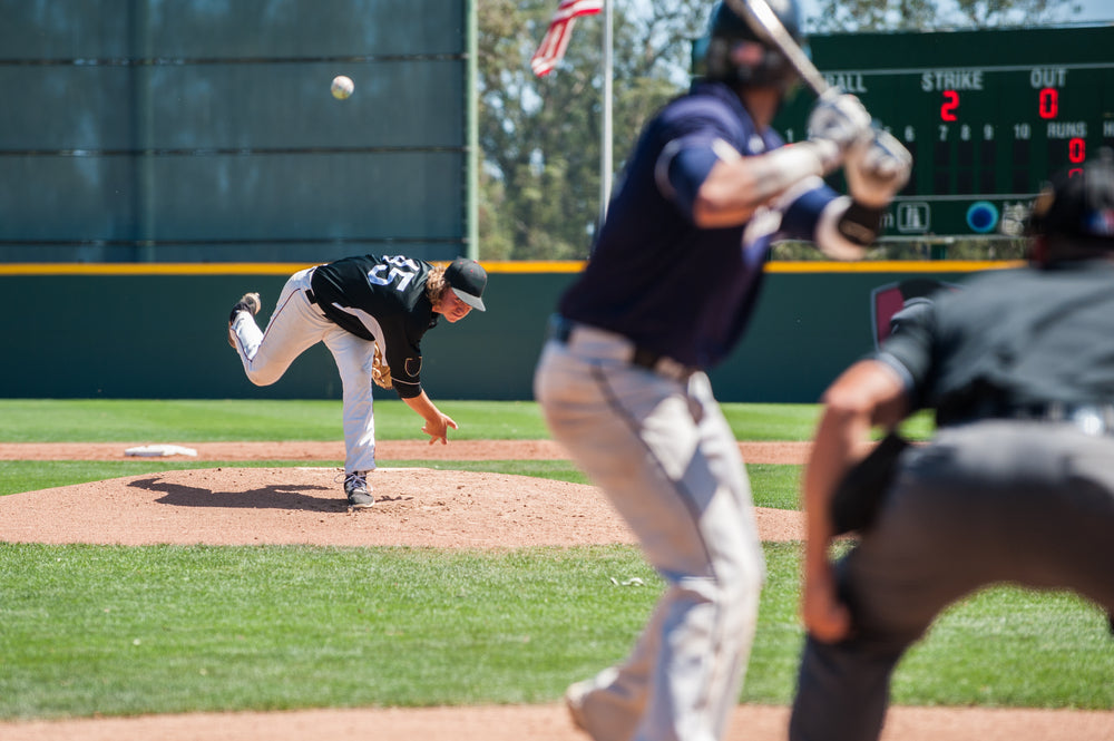 Youth baseball pitcher throwing a ball on a hot day