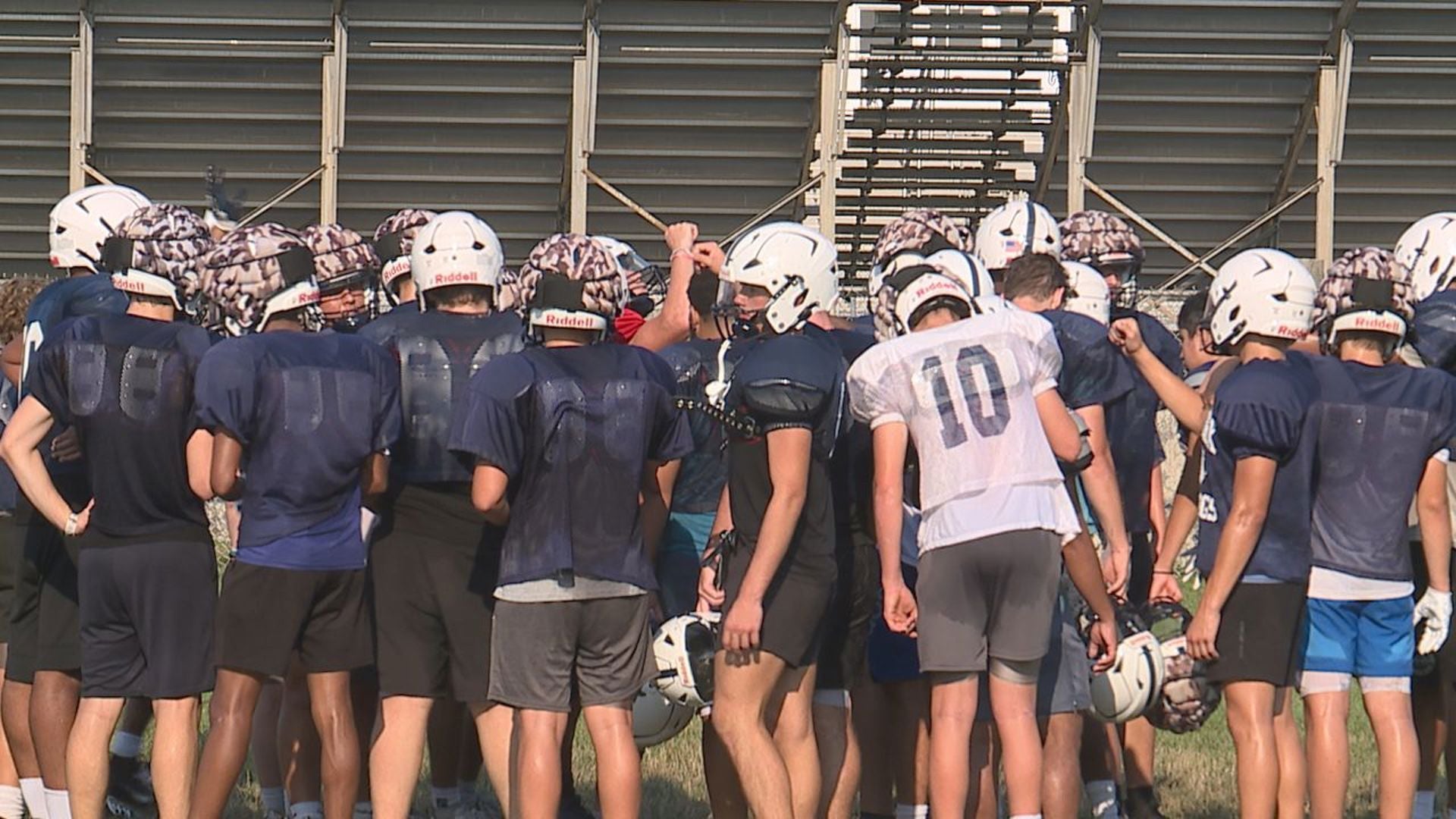 Youth football team huddling after a summer practice